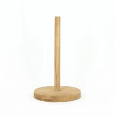 a wooden stick is standing on top of a round stand with a white surface behind it