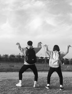 two people standing on top of a field with their arms in the air