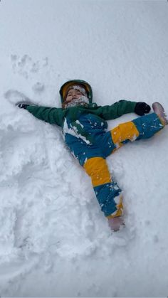 a person laying down in the snow with their arms out and legs spread out,