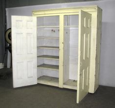 an empty room with two open doors and shelves in the corner, one is white