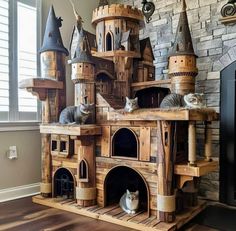 a cat house made out of wood with two cats sitting on the top and bottom