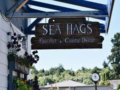 a sign for sea hags fine art and coastal decor hanging from the side of a building