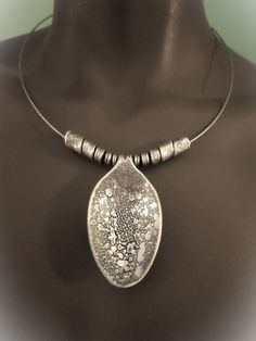 a necklace with a silver pendant on top of a mannequin's torso