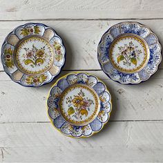 three blue and white plates sitting on top of a wooden table