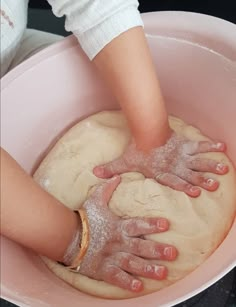 someone is kneading dough in a pink bowl