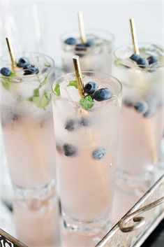 four glasses filled with ice and blueberries on a tray