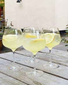 three glasses filled with lemonade sitting on top of a wooden table