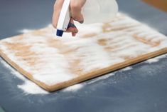 someone is using a plastic bottle to spray down the foam on top of a cutting board