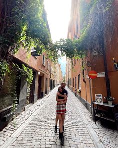 two people hugging each other on a cobblestone street