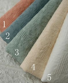 four different colors of towels on top of a white bed sheet with numbers in the middle