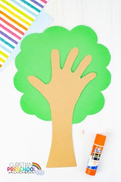 a paper cut out of a tree with paint next to it and a crayon stick