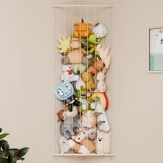 there is a rack full of stuffed animals on the wall next to a potted plant