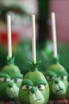 there are some green cake pops with angry faces on them and candles in the shape of heads