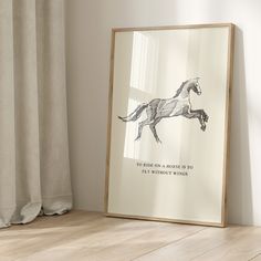 a framed poster with a horse drawn on it sitting next to a window and curtain