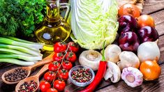 an assortment of vegetables and spices on a wooden table with herbs, garlic, tomatoes, lettuce