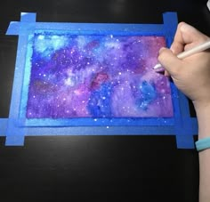 a person is drawing with colored pencils on a piece of paper that looks like a painting