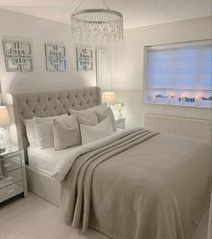 a bedroom with a large bed, chandelier and two mirrors on the wall