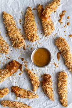 chicken wings with dipping sauce on the side and some bread crumbs around them