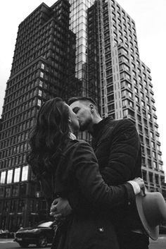 a man and woman kissing on the street in front of tall buildings with skyscrapers behind them