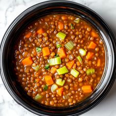 a bowl filled with beans, carrots and celery on top of a table