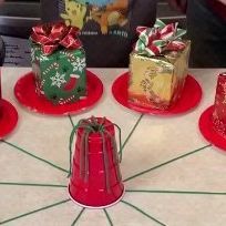 four small red plates with wrapped presents on them, sitting on a white counter top