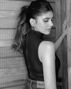 black and white photograph of a woman leaning against a wall with her hand on the door