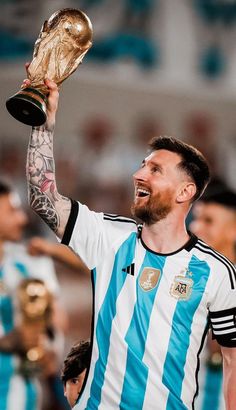 a man holding up a soccer trophy in his right hand and smiling at the camera