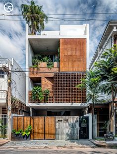 an apartment building with wooden balconies and plants on the balcony, in front of palm trees