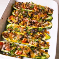 stuffed zucchini boats with meat and vegetables in a white dish on a wooden table