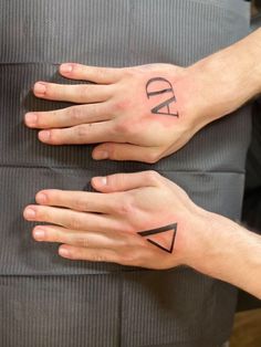 two hands with tattoos on their fingers and one has the word dad written on it