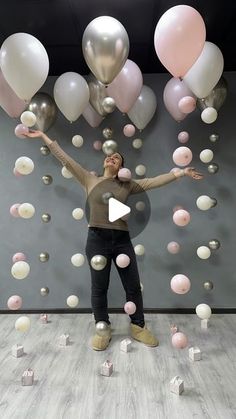 a woman standing in front of balloons and cubes with her arms spread out to the side