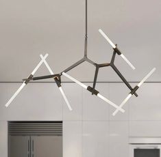 a modern chandelier hanging from the ceiling in a kitchen with stainless steel appliances