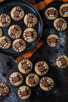 chocolate chip cookies decorated with marshmallows and spider web on a black plate