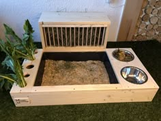 a wooden box with two metal bowls in it and some plants growing out of the top