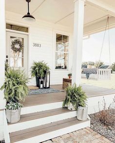 a porch with potted plants on the front steps and an entry way leading up to it