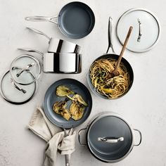 various pots and pans with food in them on a table next to utensils