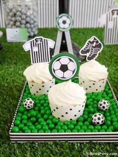 some cupcakes are sitting in the grass with soccer decorations on top of them