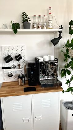 a coffee machine sitting on top of a wooden counter next to a potted plant