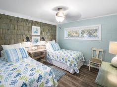 two beds in a room with blue walls and wood flooring next to each other