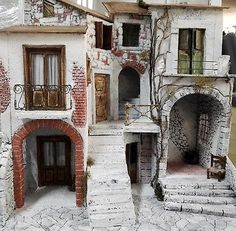 a doll house made out of clay with stairs leading up to the front door and windows