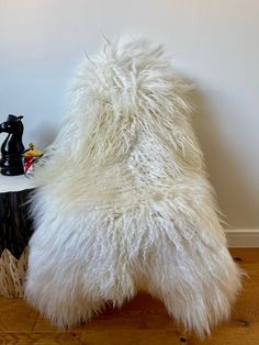 a white furry chair sitting on top of a hard wood floor