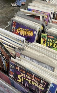 many comics are stacked on top of each other in a bin for sale at the store