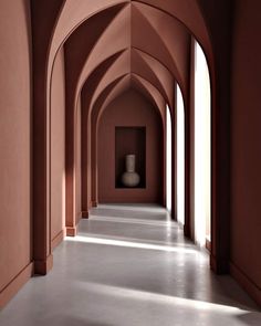 an empty hallway with pink walls and arches