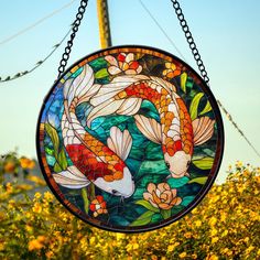 a stained glass window hanging from a chain in front of yellow flowers and power lines