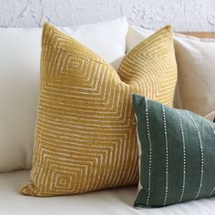 three pillows sitting on top of a white couch