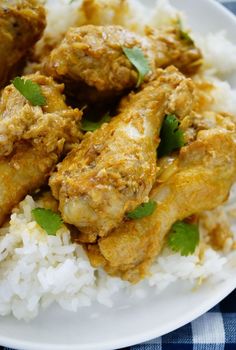 a white plate topped with meat and rice on top of a blue checkered table cloth