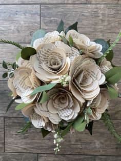 a bouquet of flowers made out of old book pages is shown on a wooden surface