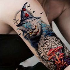 a cat wearing a witches hat and holding a clock tattoo on the left upper arm