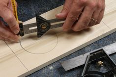 a man is working on a piece of wood with a pair of scissors and tape