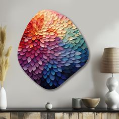 a colorful wall hanging on the side of a white wall next to a vase and lamp